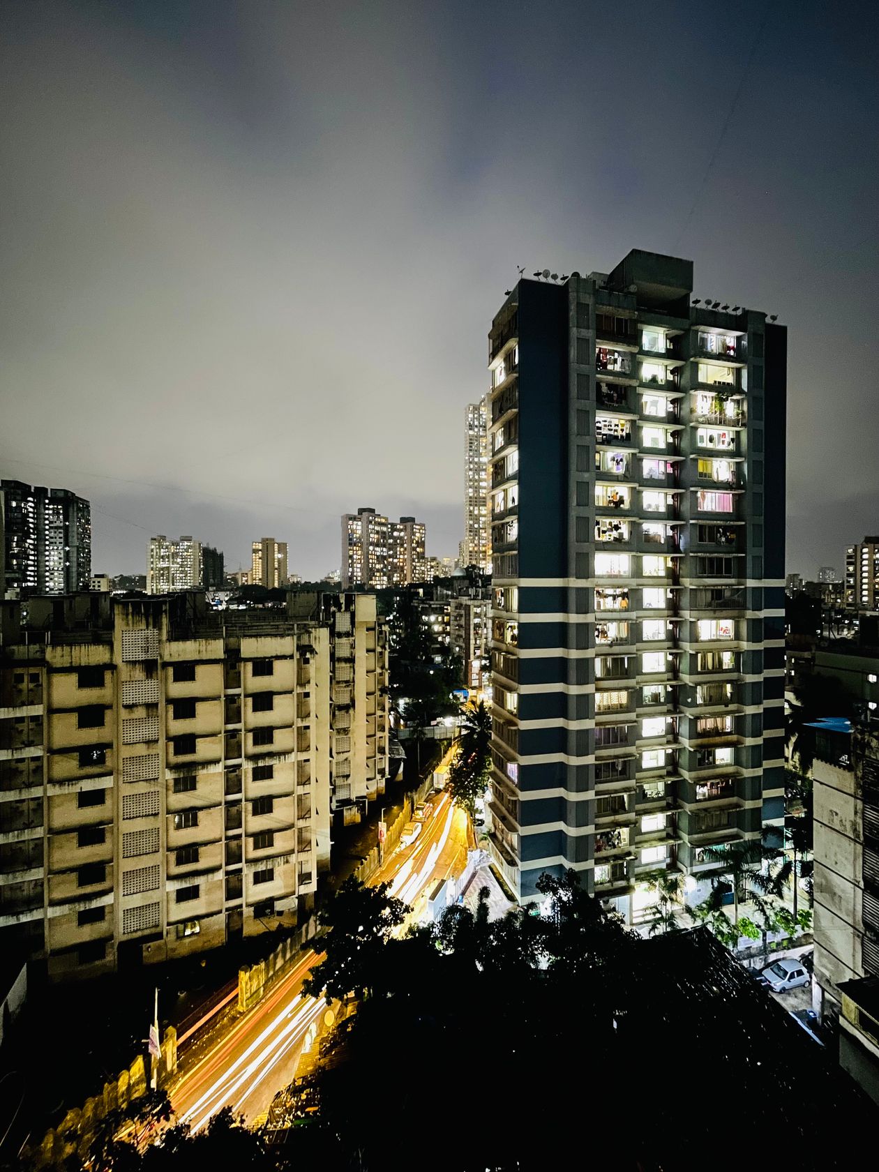 High-rise apartment buildings against an Indian city skyline at dusk