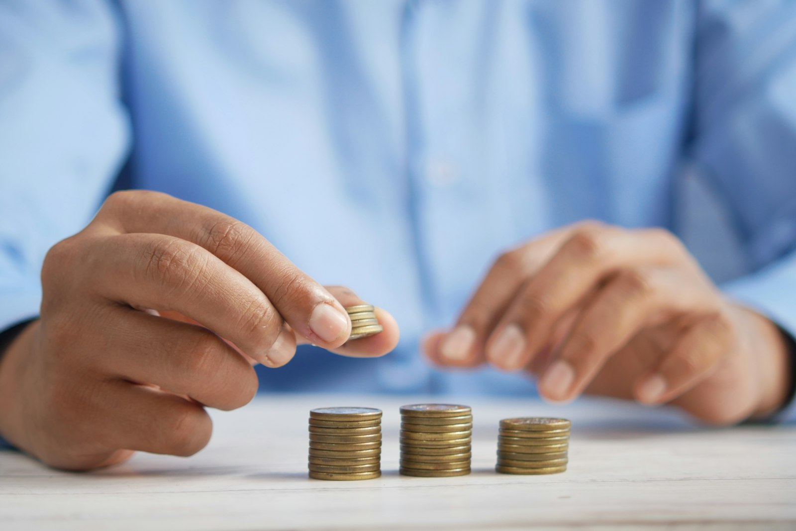 Person stacking coins representing the NRI guide to buy property in Bangalore from Saudi Arabia