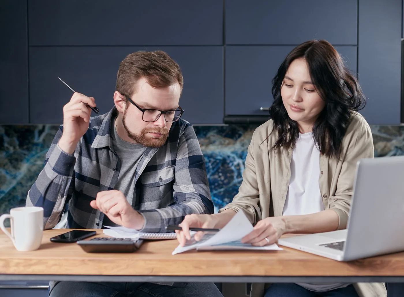 Couple looking at a paper and a calculator on a desk