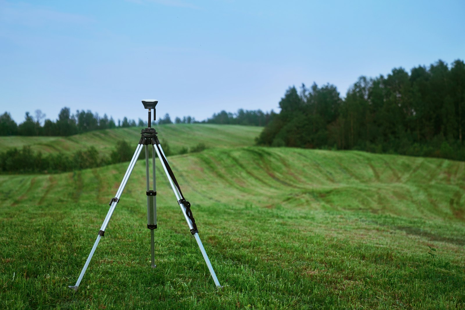 Surveying tripod on a grass field representing the legal checklist before buying plots in Bangalore