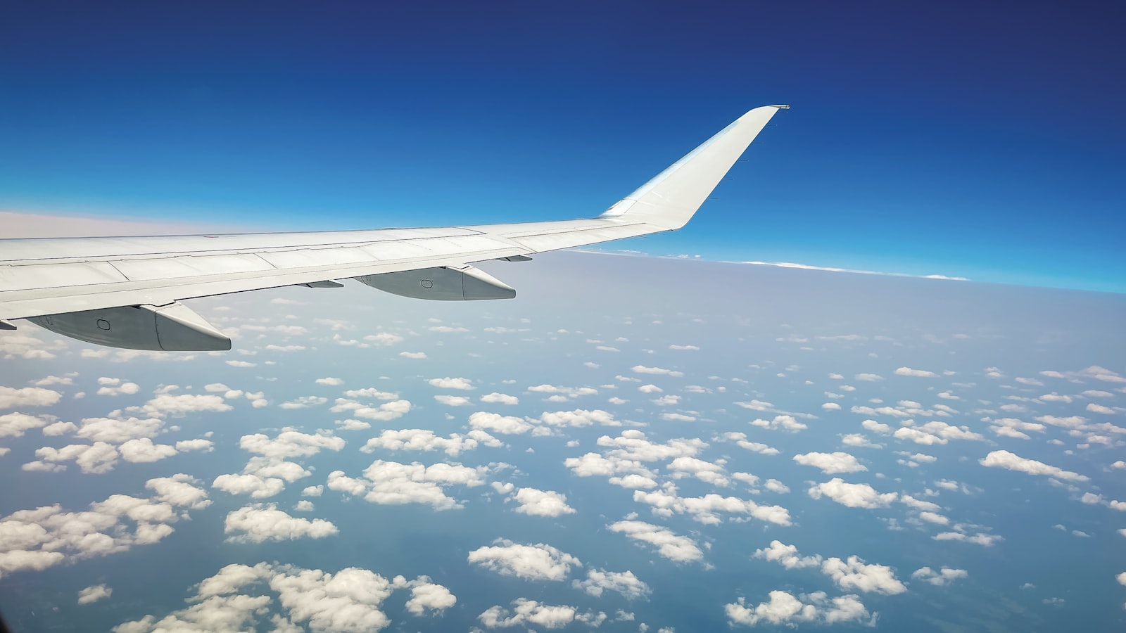 Airplane wing above clouds, representing Oman to Mangalore air connectivity