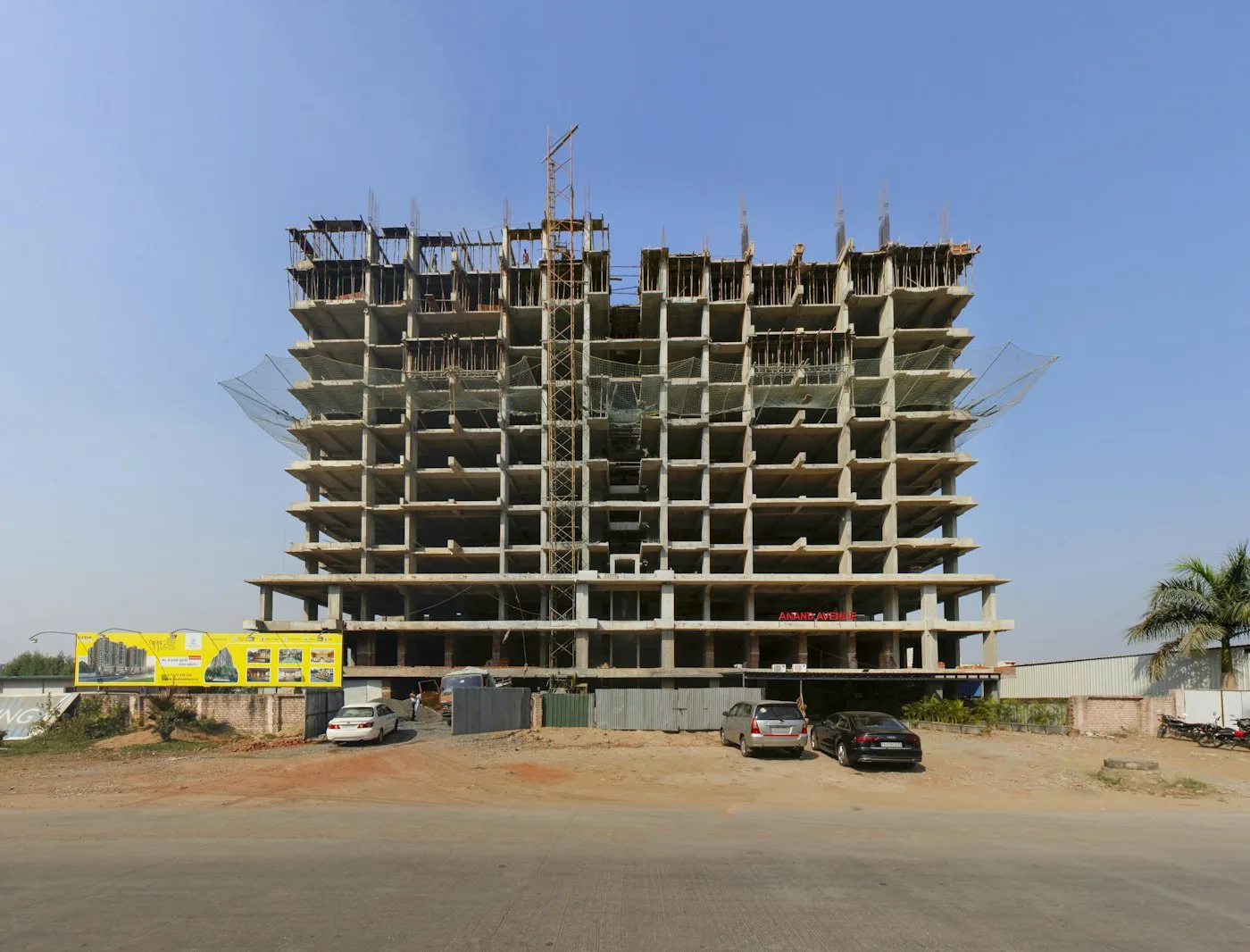 Large building under construction with cars parked in front