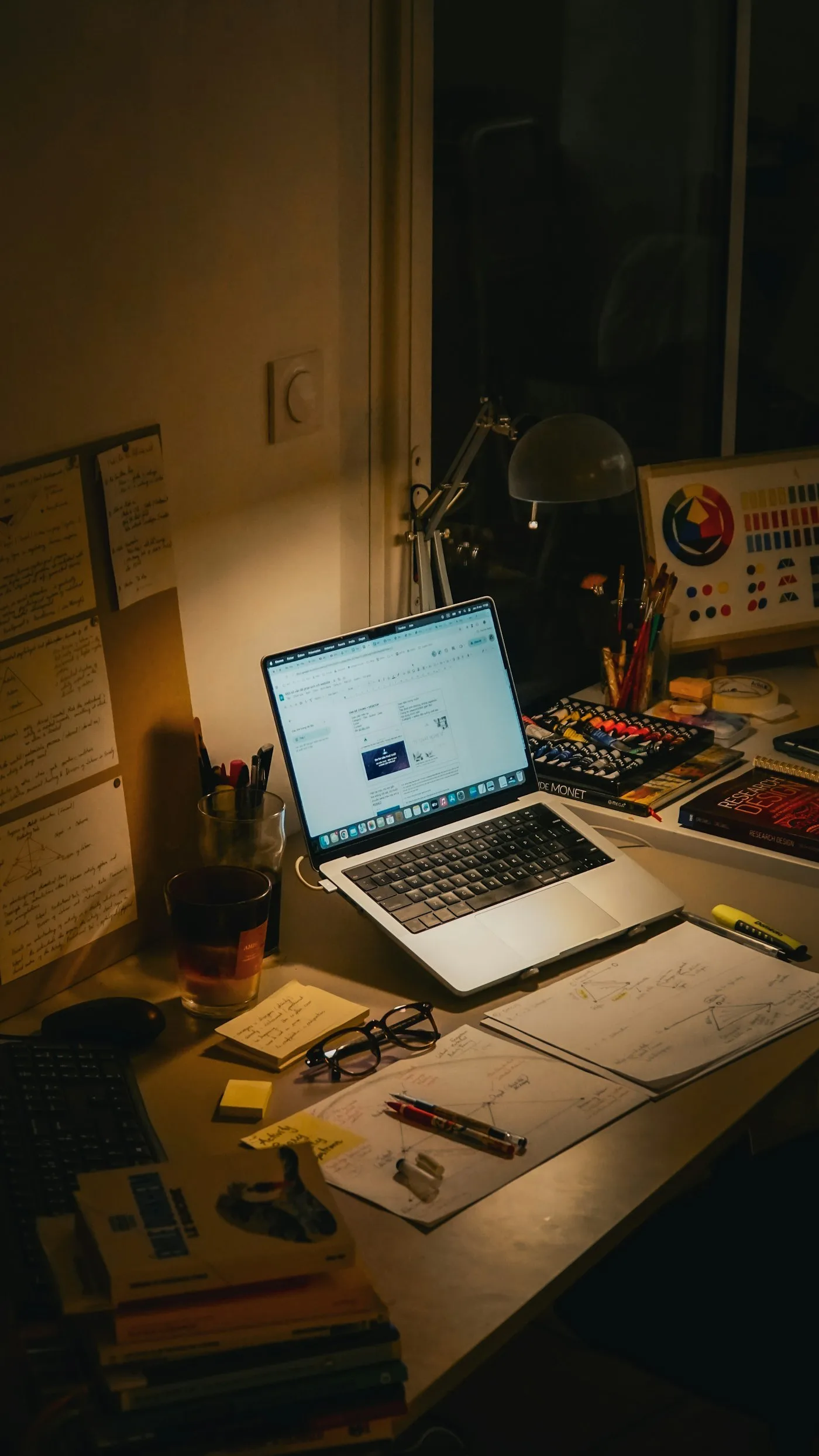 Desk with a laptop, books and papers at night