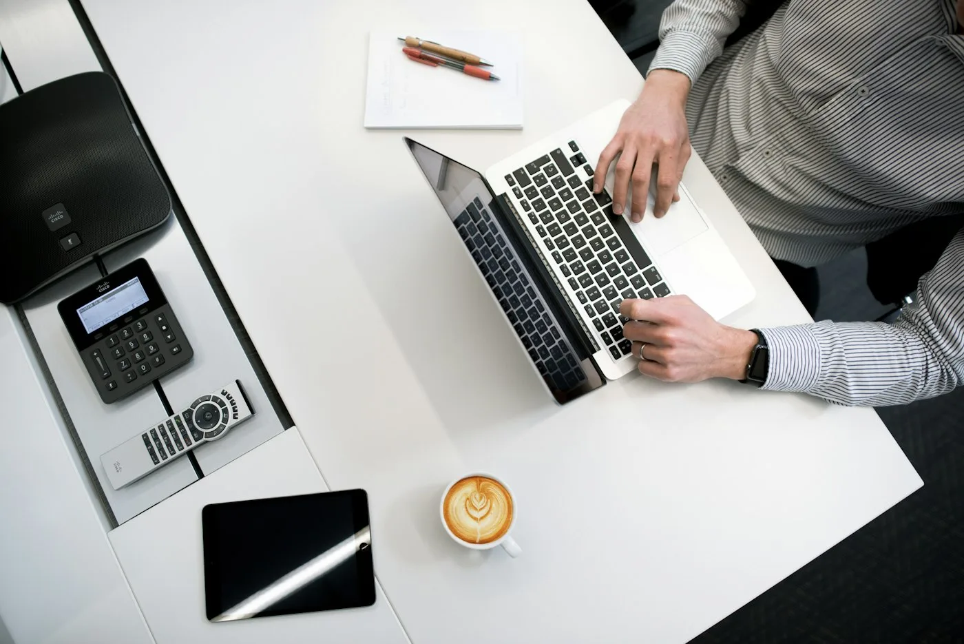 Person using a laptop on a white wooden table