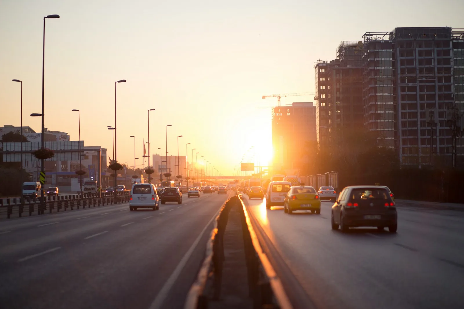Vehicles on a highway beside buildings at golden hour used as an illustration